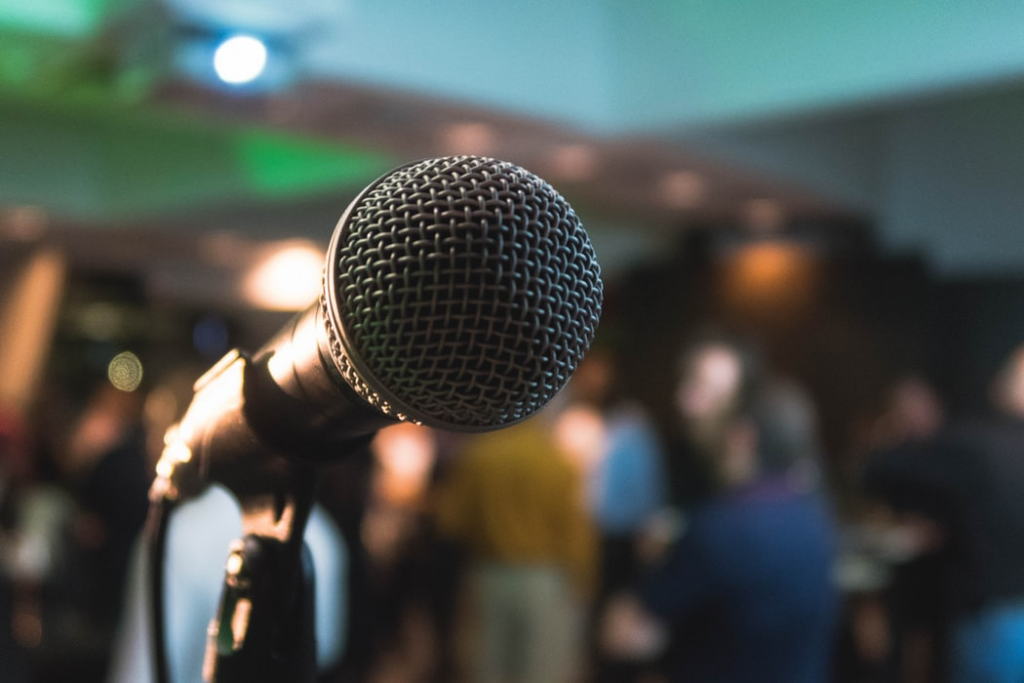 Close up photo of a microphone with a crowd in the background blurred.